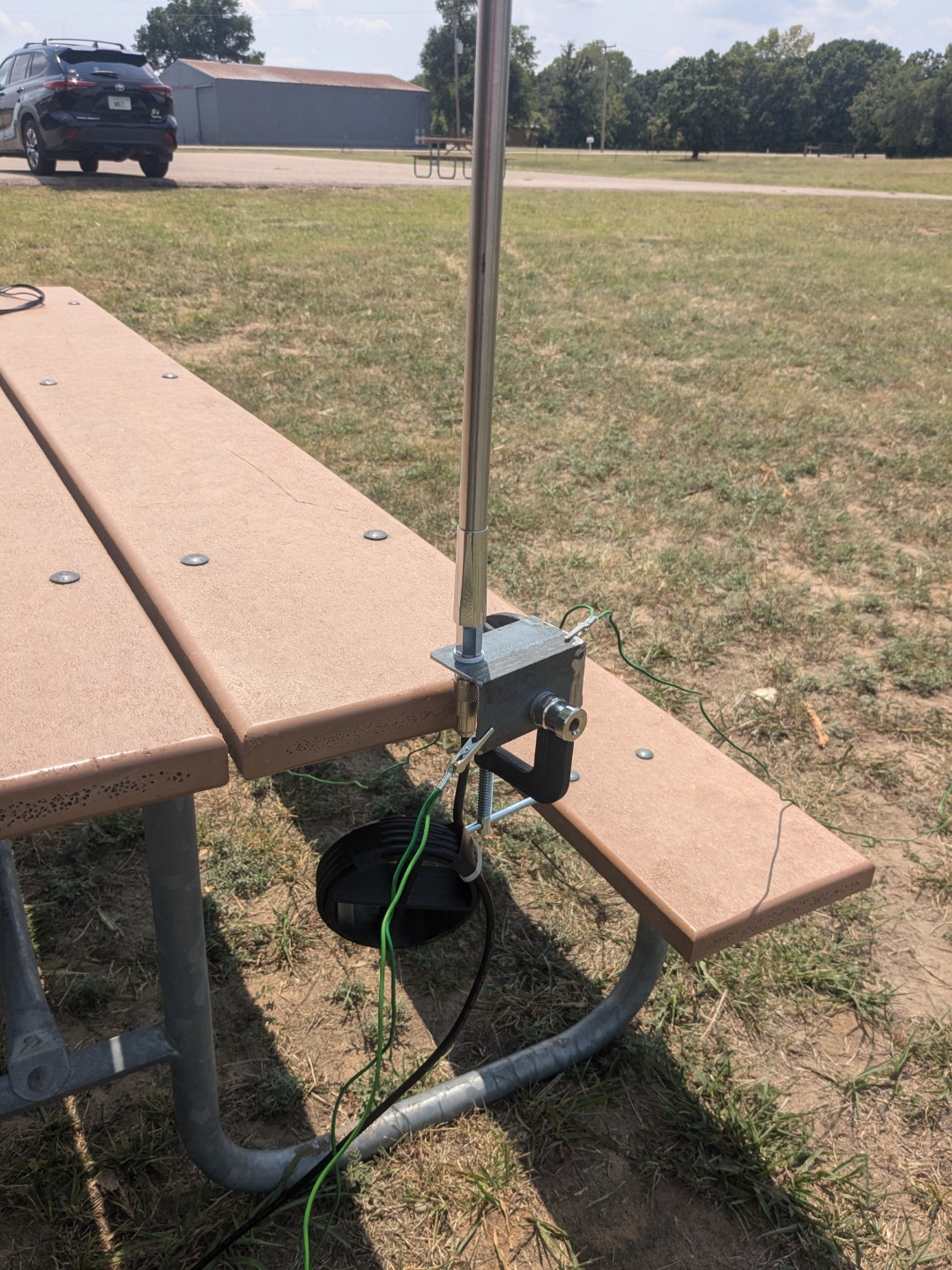 The C-clamp mount for the vertical antenna, attached to a park bench.