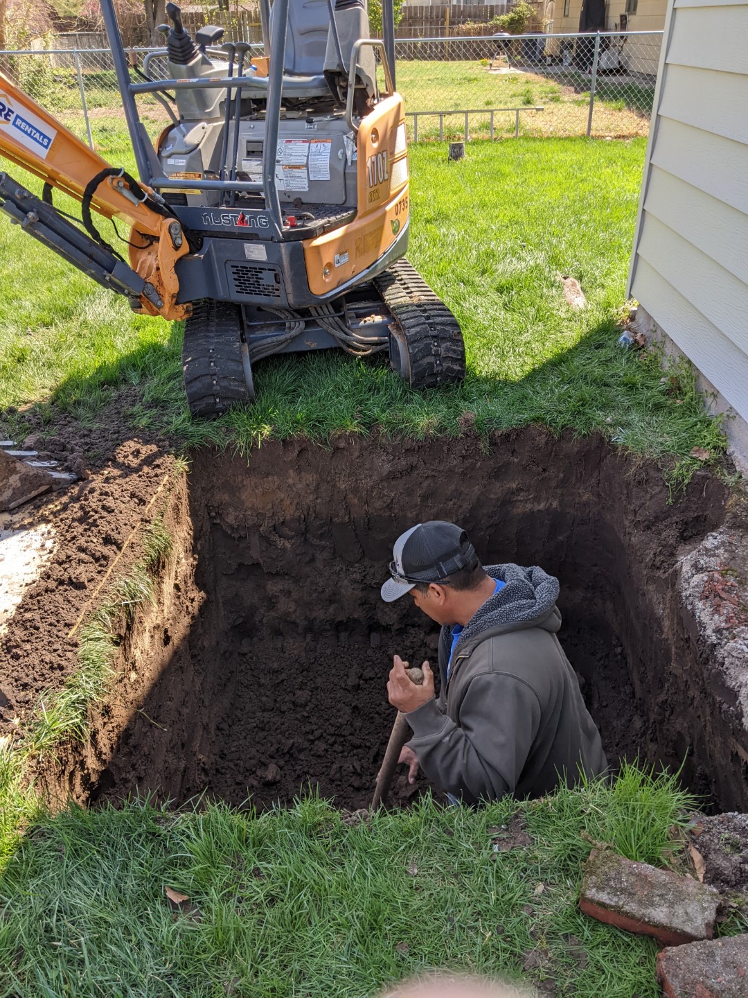 The construction worker digging out the final bits of dirt from the newly dug base..